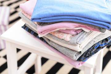 Wall Mural - Stack of folded clothes on wooden stool closeup