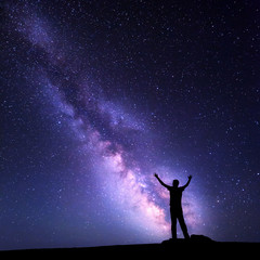 Wall Mural - landscape with colorful purple milky way. night sky with stars and silhouette of a happy man with ra