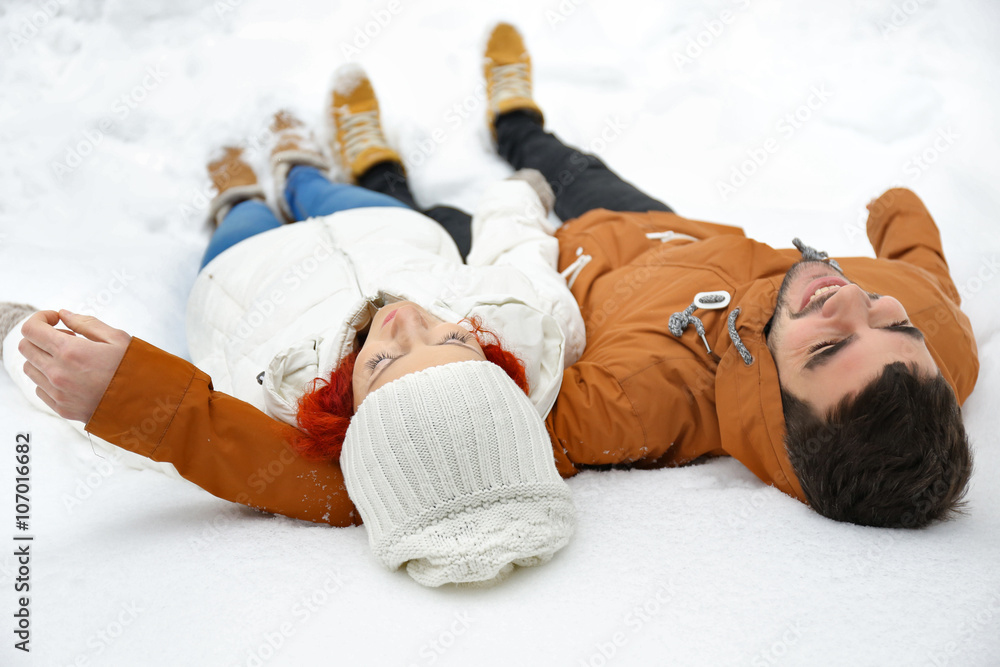 Young couple lying on the snow outdoors in winter