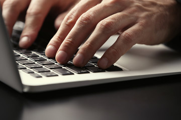 Canvas Print - Male hands typing on laptop keyboard at table closeup