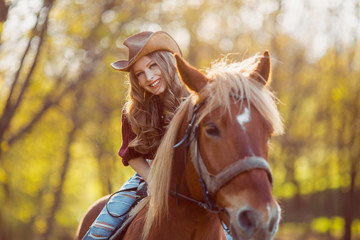 Beautiful smiling girl riding horse on autumn field