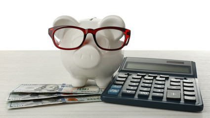 Poster - Piggy bank with dollar banknotes, glasses and calculator on white background