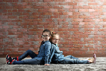 Two stylish little girls on wall background