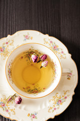 Vintage cup of tea with rosebuds, on black background