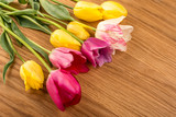 Fototapeta Tulipany - Pink and yellow tulips on wooden table.