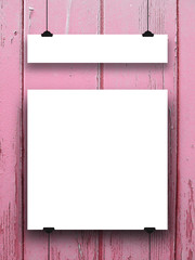 Close-up of two square and rectangular blank frames hanged by clips against pink painted weathered wooden background 