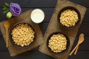 Wall Mural - Honey flavored breakfast cereal in three rustic bowls with a glass of milk and wooden spoons on the side, photographed overhead on dark wood with natural light