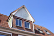 Old house with dormer and blue sky. Close-up of the roof of an old house with dormer.