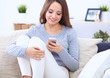 © shefkate - Pretty girl using her smartphone on  couch at home in the living room