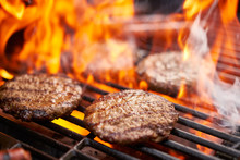 Hamburgers And Hot Dogs Cooking On Grill With Flames