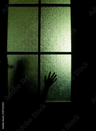 Blurred Silhouette Of A Child Behind A Glass Door In The Darkness