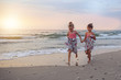 © ambrozinio - Young girls running around barefoot on the beach