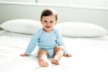 cute baby boy sitting on bed at home
