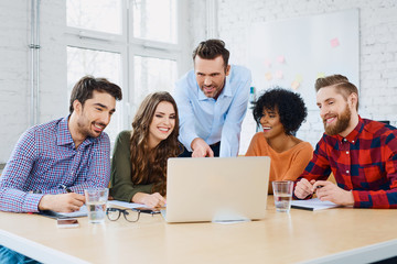 Creative agency coworkers discussing new project on laptop