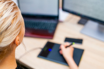 Young businesswoman using her touchpad and laptop. She is sittin