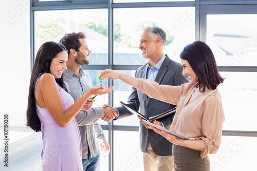 Cuadros en Lienzo Real estate agent handing over house key to young couple