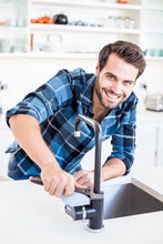Portrait Of Happy Man Fixing Tap With Tool In The Kitchen