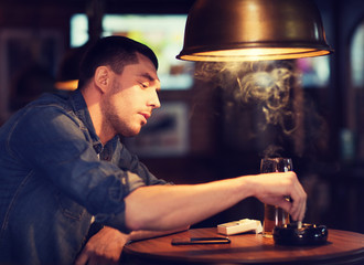 Canvas Print - man drinking beer and smoking cigarette at bar