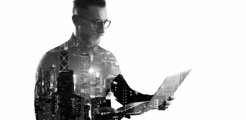 Wall Mural - Double exposure bearded businessman wearing black shirt and glasses. Banker holding contemporary notebook hands,using online payments. Modern skyscraper city at night background. Wide mockup
