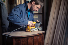 Carpenter Restoring Furniture With Belt Sander