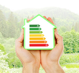 Sticker - Female hands holding house with energy efficiency scale image on natural background