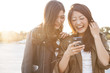 © Monet - Two young women are laughing to see the smartphone together