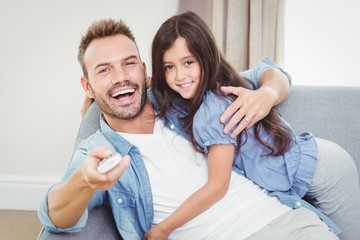 Portrait of smiling daughter hugging father sitting on sofa 