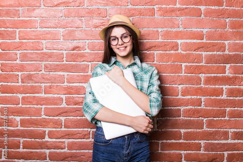 Fotografie, Tablou Beautiful young dark-haired girl in casual clothes, hat and eyeglasses posing,