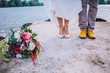 Bride and groom in bright shoes on the pier with boquete. Groom in yellow shoes