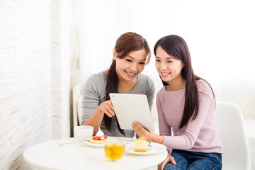 Wall Mural - Two woman use of tablet together inside coffee shop