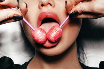 Woman licking  red shiny lollipops