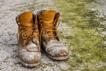 Old Worn Work Boots On Grungy Dirty Ground Background