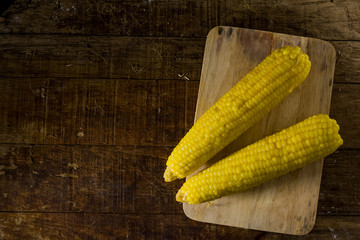 2 fresh corn on chopping block and the wood table.