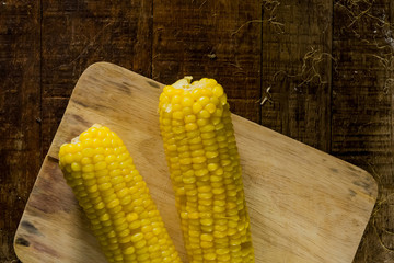 2 fresh corn on chopping block and the wood table.