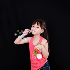 Wall Mural - Happy girl play with soap bubbles isolated black background