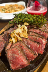 A selection of grilledT Bone steak pieces roasted garlic and rosemary, off the bone on a metal plate