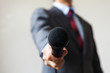 © twinsterphoto - Man in business suit holding a microphone conducting a business interview, journalist reporting, public speaking, press conference, MC