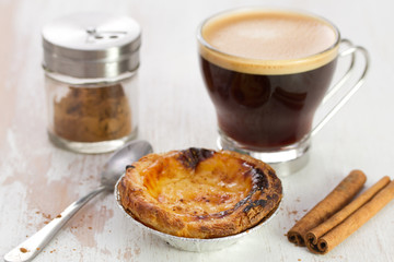 portuguese dessert pasteis de nata on white dish and cup of coffee on white wooden background