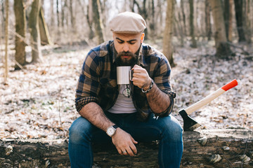 Wall Mural - Bearded man drinking coffee in the wood