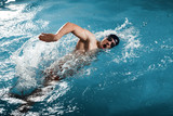Fototapeta Łazienka - Young man swimming the front crawl in a pool