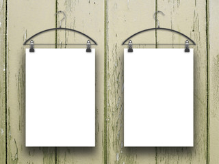 Close-up of two blank frames hanged by clothes hangers against light brown wooden background