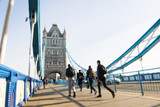Fototapeta Londyn - Out-of-focus image of unrecognisable pedestrians crossing Tower Bridge.