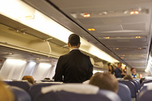 Interior Of Airplane With Passengers  And Stewardess Walking The Aisle