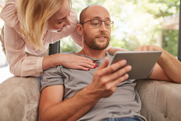 Happy couple at home using digital tablet