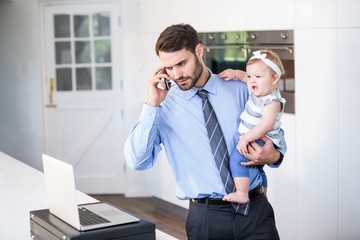 Wall Mural - Businessman looking in laptop while carrying daughter