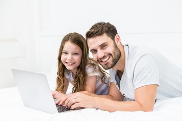 Canvas Print - Happy father and daughter using laptop on bed