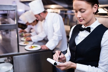 waitress with note pad in commercial kitchen