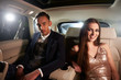 © Monkey Business - Attractive young couple in the back of a limo look to camera