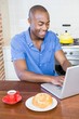 © WavebreakmediaMicro - Young man having breakfast and using laptop