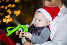 Close Up Of Mother Holding Baby Girl With Christmas Ornament